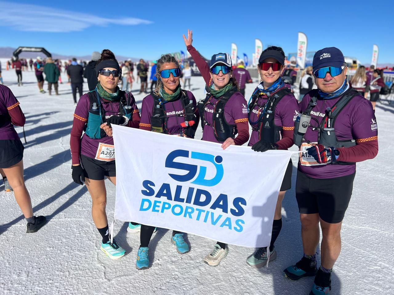 Grupo de cinco corredores con la bandera de Salidas Deportivas en las Salinas Grandes