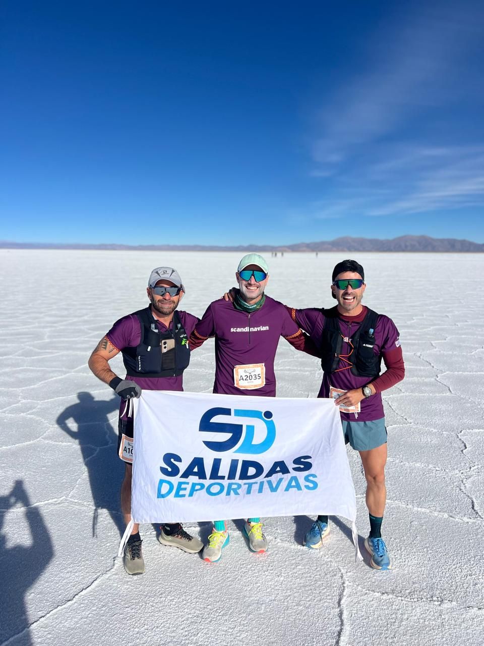 Tres corredores con la bandera de Salidas Deportivas en las Salinas Grandes